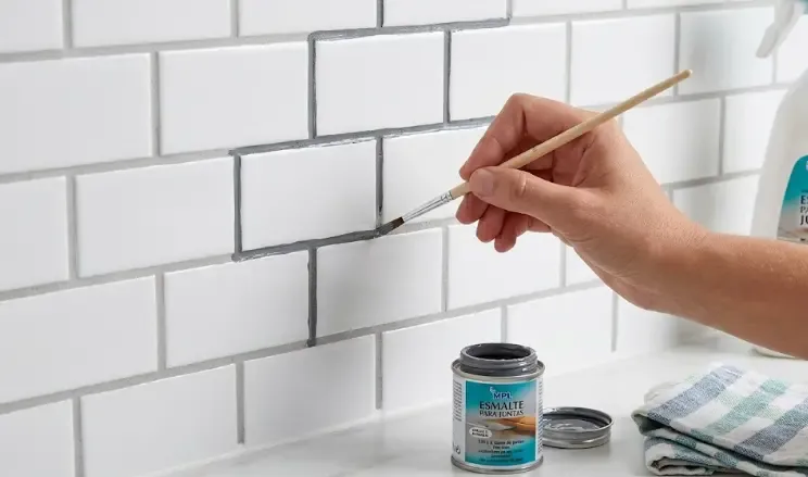 Proceso de aplicación de esmalte para juntas con pincel fino en cocina antigua