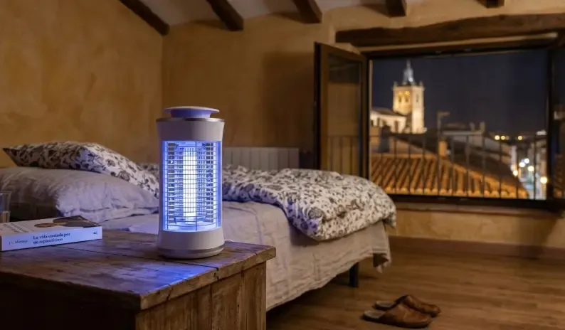 Una lámpara UV atrapamosquitos de diseño moderno encendida con luz azul violeta en una mesita de noche oscura